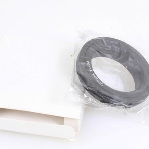 May include: A black metal step-up ring for camera lenses. The ring is labelled "Opteka T2-OM".