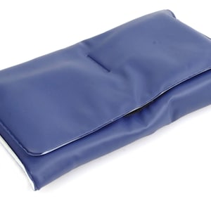 May include: A navy blue clutch with a flap closure. The clutch is rectangular and appears to be made of a smooth, possibly leather-like material. The interior edge is white.