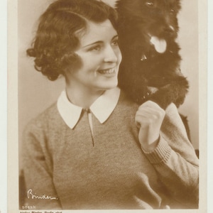 Mujer con un perro apenas encajado en su hombro. 1930. Berlín. Postal de la foto.