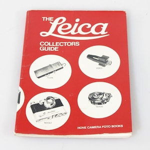 May include: A red softcover book titled The Leica Collectors Guide by Hove Camera Foto Books. The cover features white text and four circular white insets displaying black and white photographs of camera equipment labeled Flein, Video, Mooly, and Tahoo.