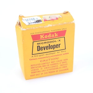 May include: A vintage Kodak Microdol-X Developer box. The yellow box has red and black text, including "Kodak" and "Developer." The box also includes a warning label. The box is for photographic purposes only.
