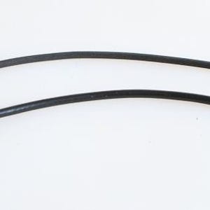 May include: Two black camera shutter release cables with silver metal ends. One cable is longer than the other. The cables are curved and lie on a white surface. The cables are used to trigger the camera shutter.