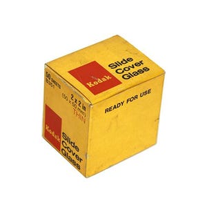 May include: A yellow Kodak box of slide cover glass. The box has red and black text that reads "Slide Cover Glass" and "2x2 in (50 x 50 mm) Thin". The box contains 50 sheets and is labeled "Ready for Use".