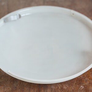May include: A white round ceiling light fixture with metal clips on the edges.