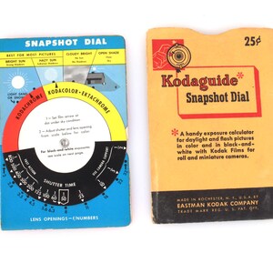 May include: Two vintage Kodak Snapshot Dial exposure calculators. One is blue with a rotating dial and text, the other is yellow with red text and a price of 25 cents. Both are for daylight and flash pictures.