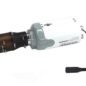 May include: A security camera with a white and grey body and a black lens. The lens has the text "OPEN" and "CLOSE". The camera has a black power cord and the text "SUPER CIRCUITS" on the side.