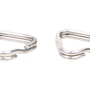 May include: Two silver-colored, double D-rings. Each ring is made of a single piece of metal bent into a D-shape, with a small, curved section at the bottom. The rings are set against a white background.