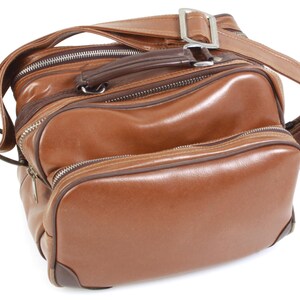 May include: A brown leather travel bag with a zippered closure and a shoulder strap.