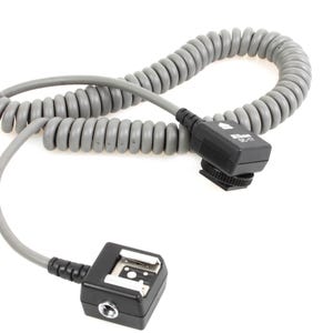 May include: A gray coiled flash sync cord with black connectors. The cord has a coiled section and two black connectors with a hot shoe mount and a port. The Nikon logo is visible on one connector.