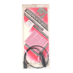 May include: A black Paramount heavy-duty sync cord in a clear plastic package with a red and white label. The label reads "Paramount Heavy Duty Sync Cords Made in USA". The cord is coiled inside the package.