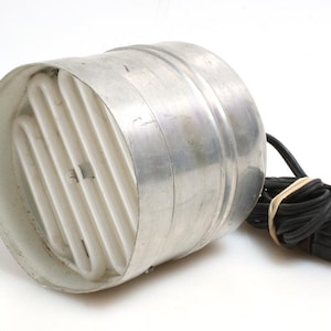 Könnte beinhalten: Ein silberner Metallventilator mit einem weißen Kunststoffgitter und einem schwarzen Stromkabel.