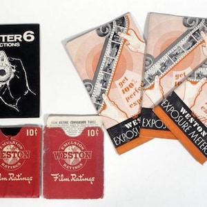 Könnte beinhalten: Sammlung von Vintage-Zubehör für Weston-Belichtungsmesser. Enthält ein schwarzes Anleitungsheft, Filmwertkarten und Werbematerialien mit dem Text "WESTON MASTER 6" und "EXPOSURE METERS".