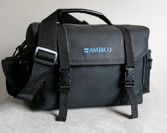May include: Black camera bag with adjustable straps and a top handle. The bag has a blue embroidered logo that says "AMBICO".