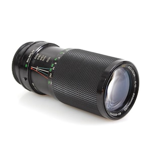 May include: A black 80-200mm zoom lens with a macro function. The lens has a black and green scale with markings for 80, 100, 120, 135, 160, and 200mm. The lens also has a depth of field scale and a focus ring.