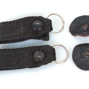 以下が含まれることがあります： 金属製のリングと黒いボタンが付いた黒いナイロンストラップ2本と、金属製のリングが付いた黒い革のパッチ2枚