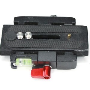 May include: Black camera quick release plate with a level and a red lever. The plate has a textured surface and three small silver screws.