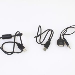 Könnte beinhalten: Drei schwarze Ladekabel mit verschiedenen Steckern. Ein Kabel hat einen USB-Stecker an einem Ende und einen Micro-USB-Stecker am anderen Ende. Ein anderes Kabel hat einen USB-Stecker an einem Ende und einen Mini-USB-Stecker am anderen Ende. Das dritte Kabel hat einen USB-Stecker an einem Ende und einen 30-Pin-Stecker am anderen Ende.