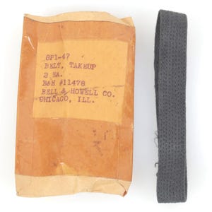 May include: An image of a gray belt next to a brown paper package. The package has text that reads "8P1-47 BELT, TAKEUP 2 EA. B&H #11478 BELL & HOWELL CO. CHICAGO, ILL."
