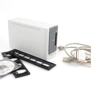 May include: A white and grey slide scanner with a CD and slide trays. The scanner is connected to a computer with a grey cable.