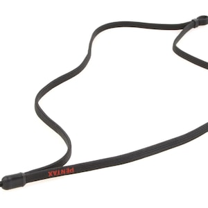 May include: Black camera neck strap with the brand name "PENTAX" printed in red. The strap is made of a flat, woven material and has an adjustable loop at one end and a plastic connector at the other.