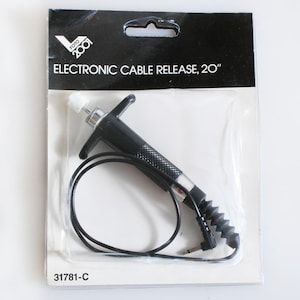 May include: A black electronic cable release with a white button and a 20-inch cord. The packaging says "ELECTRONIC CABLE RELEASE, 20" and "FOTO 2001". The product number is 31781-C.