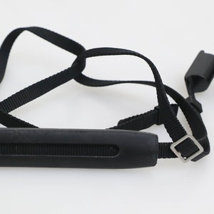 May include: Black camera strap with a padded handle. The strap has a metal buckle and a small loop at one end.