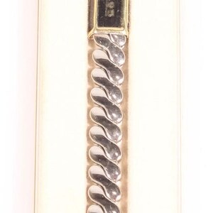 Può includere: Un orologio vintage Casey Jones nella sua scatola originale. L'orologio ha un quadrante nero rettangolare con dettagli dorati e un cinturino argentato a forma di onda. La scatola è color crema con il nome del marchio in nero.