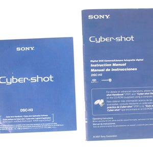 May include: Two blue Sony Cyber-shot DSC-H3 instruction manuals. The square manual features application software information, while the rectangular manual contains digital still camera operating instructions in English and Spanish text.