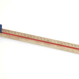 May include: A wooden architectural scale with a red center stripe and blue plastic slider. The scale is marked with measurements and is approximately 12 inches long.