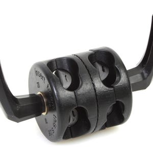 Puede incluir: Abrazadera de plástico negro con dos ganchos, diseñada para sujetar objetos a un soporte de micrófono. La abrazadera tiene un mecanismo giratorio y el texto "Insert to open" está impreso en el lateral.