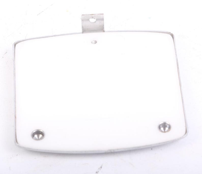 May include: A white, rectangular object with rounded corners and a silver metal frame. Two silver rivets are visible at the bottom, and a metal bracket is at the top. The object appears to be a component or part.