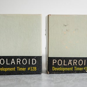 May include: Two vintage Polaroid Development Timer #128 boxes. The boxes are light green with black and yellow lettering.