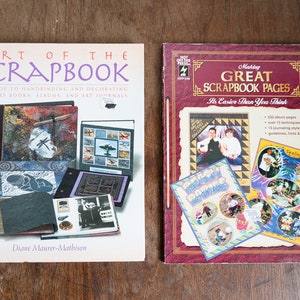 May include: Two craft books about scrapbooking. The book on the left is titled "Art of the Scrapbook" and has a white cover with colorful images of scrapbook pages. The book on the right is titled "Making Great Scrapbook Pages" and has a red cover with images of scrapbook pages.