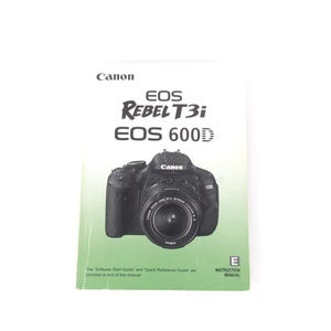 Peut inclure: Un manuel d'instruction blanc et vert clair pour l'appareil photo Canon EOS Rebel T3i EOS 600D. La couverture présente le logo Canon, les noms des modèles en texte noir et une image centrale d'un appareil photo reflex numérique noir.
