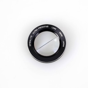 May include: A black circular Spiralite Ultra-Proxifar lens with a 58mm diameter. The lens features a split-field design with a clear glass element and white text printed on the outer rim that reads Spiralite Ultra-Proxifar Lens 58mm Japan.