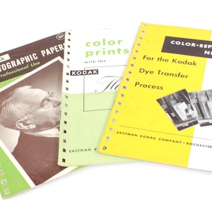 Może przedstawiać: Trzy zabytkowe instrukcje Kodak z zielonymi, żółtymi i białymi okładkami. Instrukcje są zatytułowane "Papier fotograficzny", "Odbitki kolorowe" i "Negatywy separacji kolorów".
