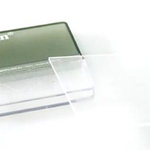 Puede incluir: Un filtro de cámara cuadrado y transparente hecho de vidrio claro, colocado junto a su estuche de almacenamiento rectangular de plástico tintado oscuro. El estuche presenta la marca Cokin impresa en blanco en la esquina superior izquierda.
