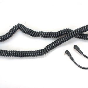 May include: A black coiled cable with two connectors on the ends. The cable is coiled and laid out on a white surface.