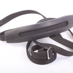 May include: Black camera strap with a padded shoulder rest. The strap has a metal buckle.
