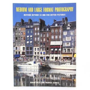 Puede incluir: Portada de libro con una foto de una ciudad costera con barcos y el título "Fotografía de formato medio y grande: Más allá de 35 mm para mejores imágenes".