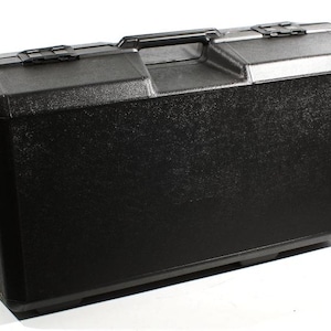 May include: A black, rectangular hard-shell case with a textured surface. The case features a handle, two latches, and a reinforced top. The case is designed for carrying and protecting items.