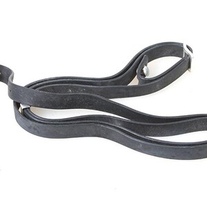 May include: A black rubber strap with metal buckles. The strap is folded in half and appears to be a camera strap.