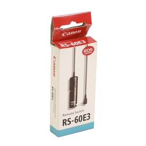 May include: A white box with a red top and a black remote switch inside. The box has the text "Canon RS-60E3" on the front and the text "Remote Switch RS-60E3" on the bottom. The box also has a small hole on the top.