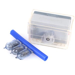 Peut inclure: Un réservoir de développement de film Kodak en plastique transparent avec un couvercle gris, un cylindre bleu et trois petites ampoules en forme de verre. Les articles sont disposés sur une surface blanche, suggérant un thème de photographie ou de chambre noire.