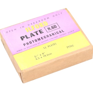 May include: A box of Ilford N.60 photomechanical plates. The box is brown with a yellow and pink label that reads "Ilford Plate N.60 Photomechanical Made in England by Ilford Limited (Ilford Essex) 12 Plates 3" x 4" 8.2 x 10.2cm 7778E".