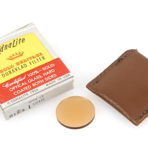 May include: A brown leather case with a gold-colored filter inside. The filter is labeled "EdnaLite Gold Heritage Duraklad Filter" and "Certified 100% - Solid Optical Glass, Hard Coated Both Sides".
