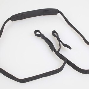 May include: A black adjustable camera strap featuring a padded shoulder section, woven nylon webbing, and two small loop attachments for securing to a camera body, complete with silver-toned metal hardware for length adjustment.