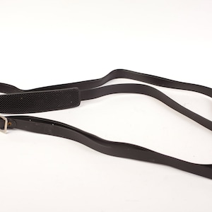 May include: A black leather camera strap with a padded shoulder rest and a silver buckle.