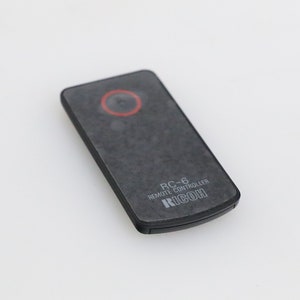 May include: A black remote control with the text "RC-6 REMOTE CONTROLLER RICOH" printed on it.