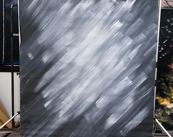 May include: A large, dark gray backdrop with white brushstrokes, mounted on a metal stand. The abstract design features diagonal strokes, creating a textured effect. The backdrop is used for photography or video production.